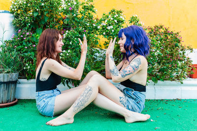 Happy young women playing patty cake in backyard