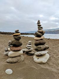 Stack of stones on beach against sky