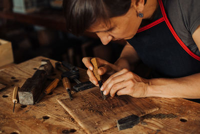 Woman engraving wooden panel using hand tools