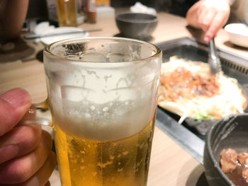 Close-up of hand holding beer glass on table