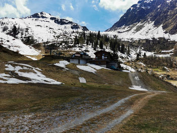 Snow covered houses by mountain against sky