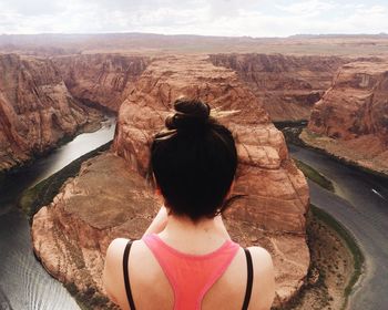 Rear view of woman standing on rock formation against sky