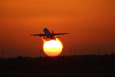 Low angle view of silhouette airplane against sky during sunset