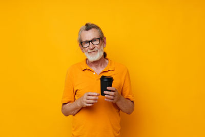 Portrait of senior man against yellow background