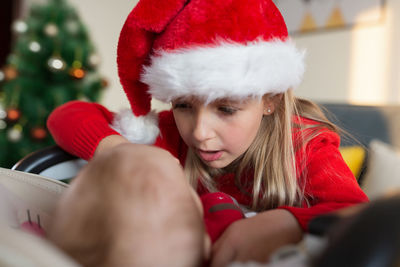 Cute girl wearing santa hat playing with sister at home