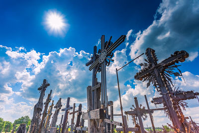 Low angle view of cross amidst buildings against blue sky