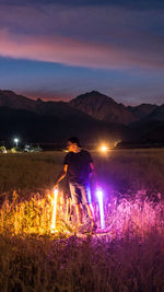 Man standing on illuminated field against sky at night