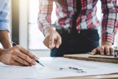 Midsection of architects making blueprint while working in office