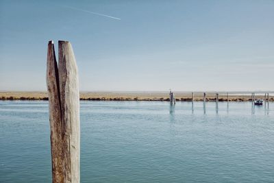 Wooden posts in sea against sky