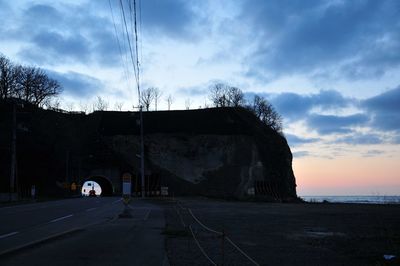 Cars on road against cloudy sky