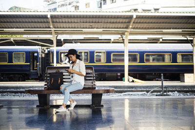 Full length portrait of man sitting at railroad station