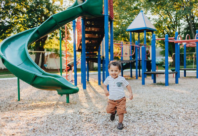 Diverse mixed race toddler boy at playground park having fun making childhood memories