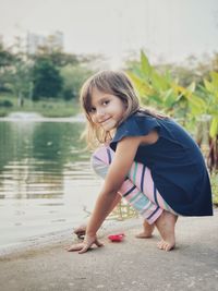 Portrait of cute girl crouching by lake