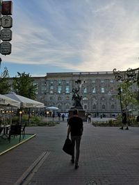 Rear view of woman walking on street against buildings in city