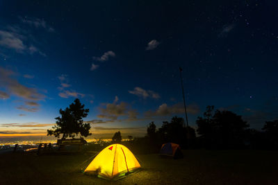 Tent on landscape against sky at night