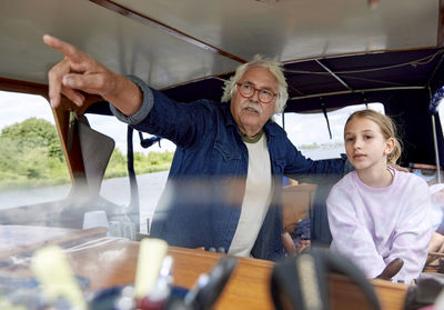 Grandfather pointing by granddaughter in boat