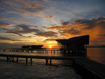 Silhouette pier on beach against sky during sunset