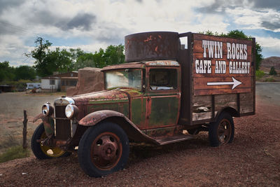 Abandoned vintage car on field against sky