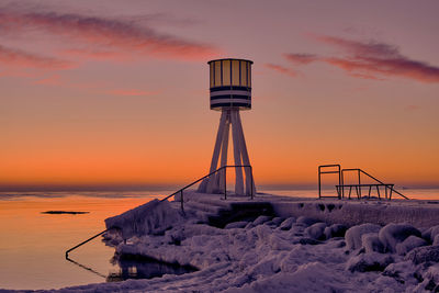 Lifeguard hut on rock against sky during sunset