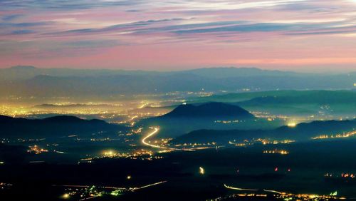 Aerial view of illuminated city against sky at sunset