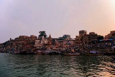 River by townscape against sky at dusk