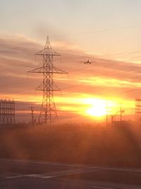 Silhouette electricity pylon against sky during sunset