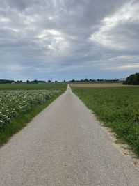 Road amidst field against sky