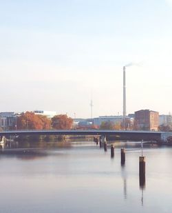 Bridge over river in city against clear sky