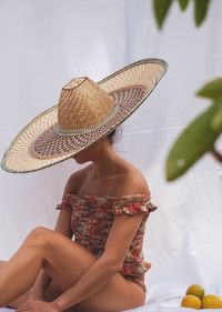 Woman with hat sitting on bed by fruits