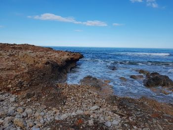 Rock formation on beach against sky