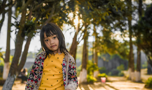 Portrait of young woman standing against trees