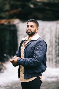 Man standing against waterfall