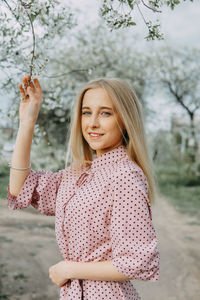 Blonde girl on a spring walk in the garden with cherry blossoms. female portrait, close-up. 