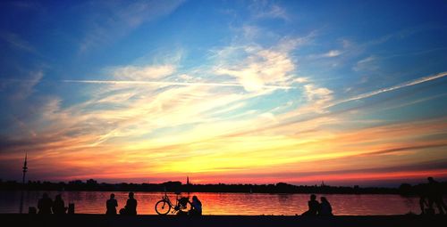 Silhouette people on beach against sky during sunset