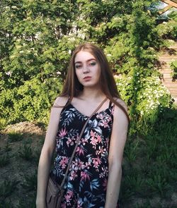 Portrait of beautiful young woman standing against plants