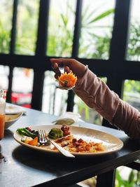 Portrait of woman holding fork with food above plate 