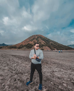 Full length portrait of young man on land against sky