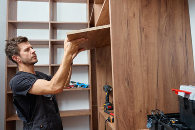 Side view of man with arms raised standing in workshop
