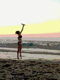 Silhouette of woman standing on beach at sunset