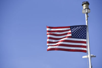 Low angle view of flag against clear blue sky