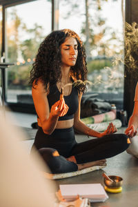 Woman holding burning sandalwood while meditating with eyes closed at retreat center