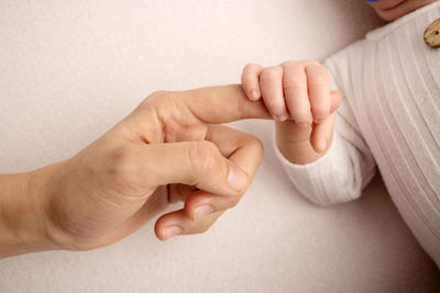 Midsection of mother holding baby hand