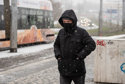 Man standing on wet street in city during winter
