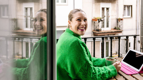 Portrait of young woman sitting on window