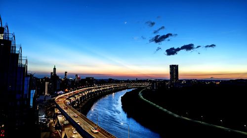 High angle view of illuminated street amidst buildings against sky