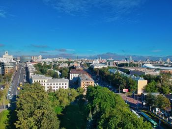 High angle view of trees and buildings against blue sky