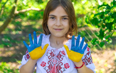 Portrait of smiling young woman standing against trees