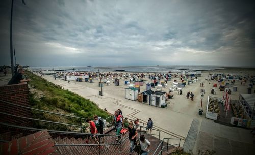 Tourists on beach against cloudy sky