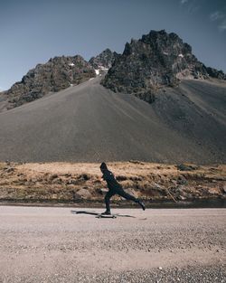 Man skateboarding on road against mountain 