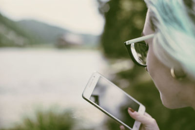 Close-up of hand holding smart phone outdoors
